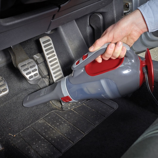 BLACKDECKER ADV1200 handheld car vacuum in use cleaning vehicle floor mat.