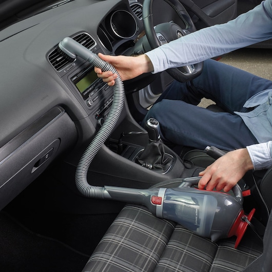 BLACKDECKER ADV1200 handheld vacuum cleaner used for car interior cleaning with hose attachment.