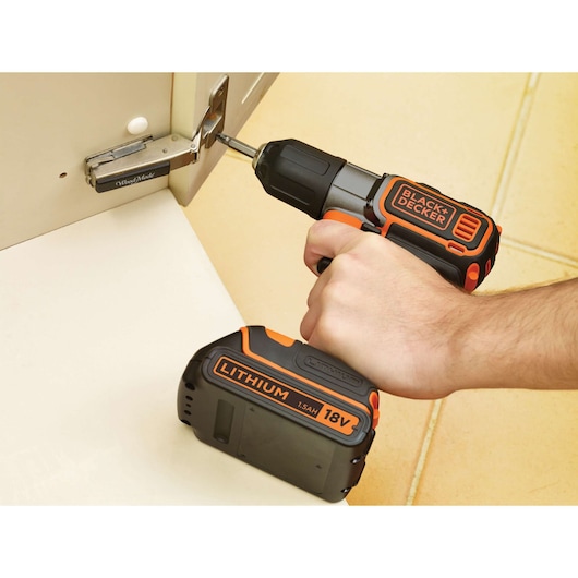 Photo of BLACK+DECKER ASD18K cordless drill with 18V lithium battery being used to fasten a cabinet hinge.