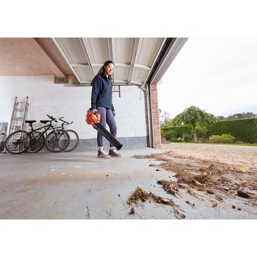 BLACKDECKER BCBL200L25 cordless leaf blower used in garage to clear leaves and debris.