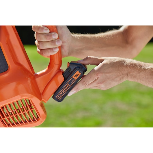BLACKDECKER BCBL200L25 lithium battery being inserted into orange cordless leaf blower close-up.
