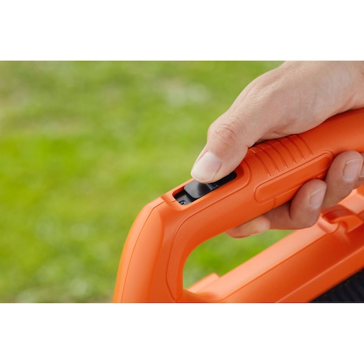 Close-up photo of a hand pressing the switch on an orange BLACKDECKER BCBL200L25 blower handle.