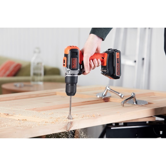 BLACKDECKER BCD003MEM2K cordless drill in use drilling wood, photo shows close-up of tool.