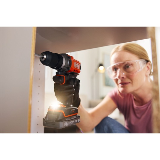 BLACKDECKER BCD382D1 cordless drill with LED light used on furniture assembly, close-up view.