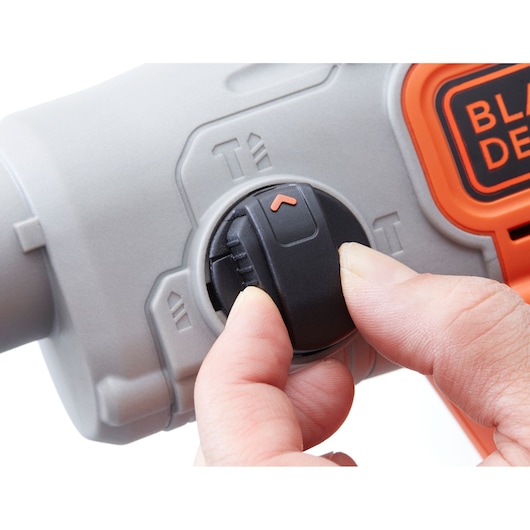 Close-up photo of someone adjusting the mode selector on a BLACKDECKER BCD900E2K power tool, showing gray and orange case.