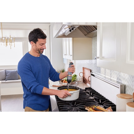 Photo of BLACKDECKER BCKM1011KGF hand blender used in a kitchen to blend soup in a white pot.