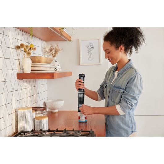 Photo of BLACKDECKER BCKM1012KB electric can opener used on a kitchen counter near stove and shelves.