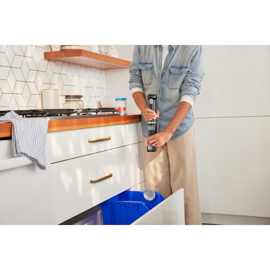 Photo of BLACKDECKER BCKM1012KB handheld can opener being used in a modern kitchen near a recycling bin.