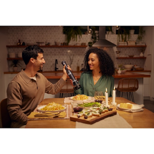 BLACKDECKER BCKM1012KB cordless kitchen tool in use at a dining table with pasta dishes and candles.