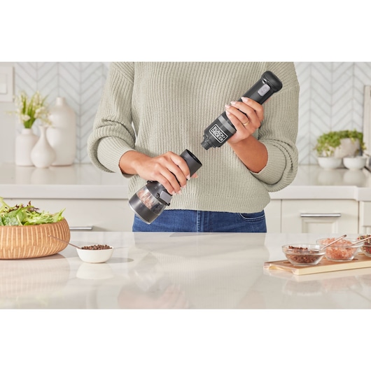 BLACK+DECKER BCKM1012KB electric grinder held in kitchen, close-up with food bowls and salad visible.