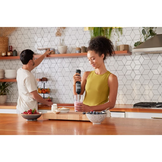 BLACKDECKER BCKM1012KB cordless hand blender in use blending smoothie in modern kitchen setting.