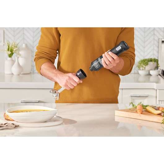 Photo of BLACKDECKER BCKM1012KB hand blender being assembled in a modern kitchen near soup and vegetables.