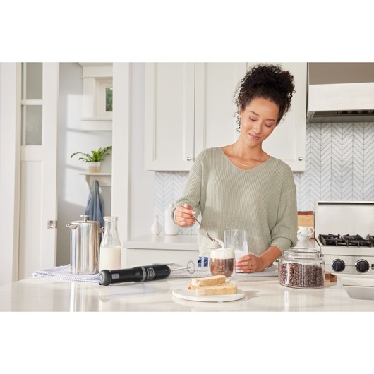 BLACKDECKER BCKM1012KB cordless hand blender on kitchen counter with coffee, milk, and bread visible.
