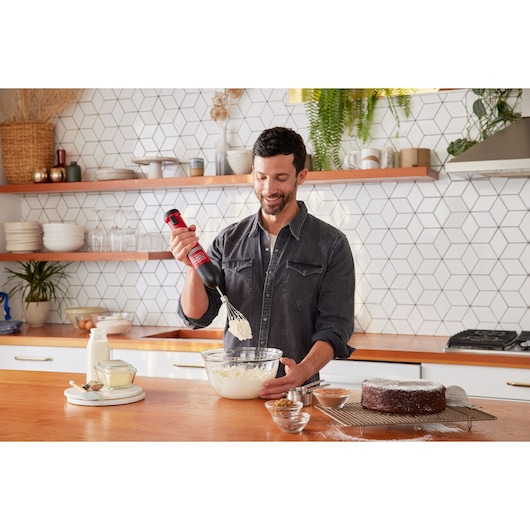 BLACKDECKER BCKM1012KR hand mixer used for whipping ingredients in a glass bowl, modern kitchen setting.