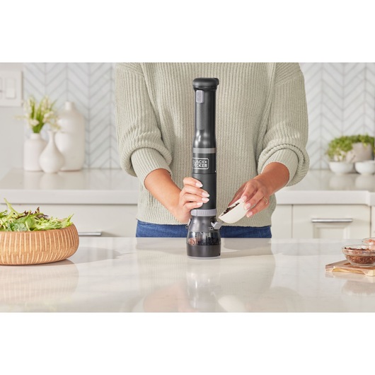 BLACKDECKER BCKM1016KSB cordless kitchen mill in use on kitchen counter, person filling grinder.