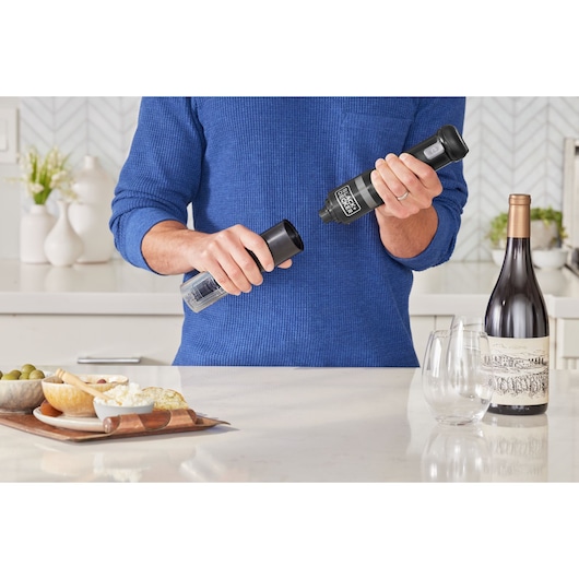 Photo of BLACKDECKER BCKM1016KSB electric wine opener held by a person in a kitchen near wine and snacks.
