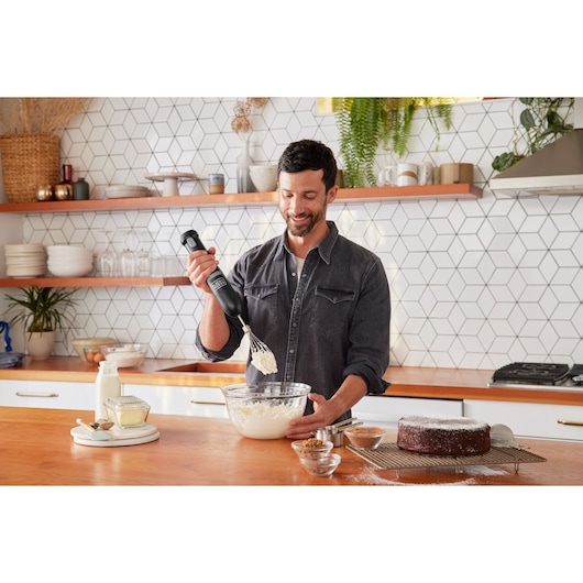 Photo of BLACKDECKER BCKM1016KSB hand mixer used for baking in a modern kitchen with a cake and ingredients visible.
