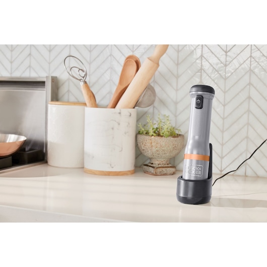 BLACK+DECKER cordless handheld kitchen mixer BCKM1016KSG charging on a countertop with utensils in the background.