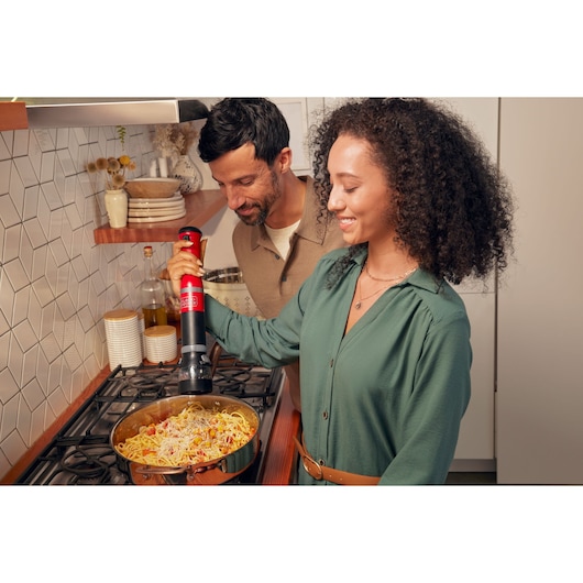BLACKDECKER BCKM101SPFF electric pepper mill used over a pan of pasta in a modern kitchen.