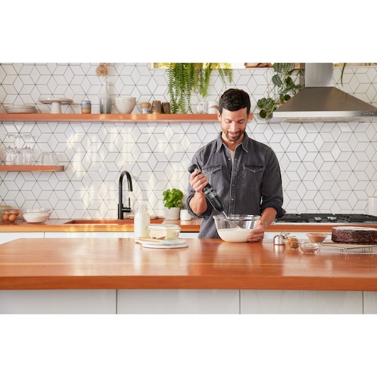 BLACKDECKER BCKM101WHFF hand mixer used in a modern kitchen with wooden countertop and baking ingredients.