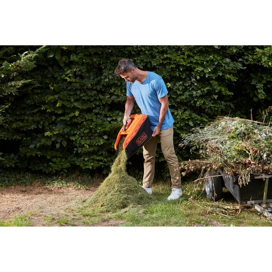 Photo of BLACKDECKER BCMW3318N lawn mower grass box being emptied outdoors.
