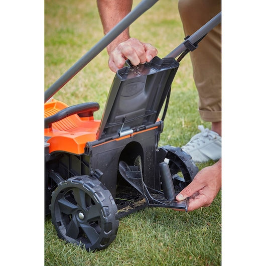 BLACKDECKER BCMW3318N lawn mower rear discharge compartment open, close-up view on grass.