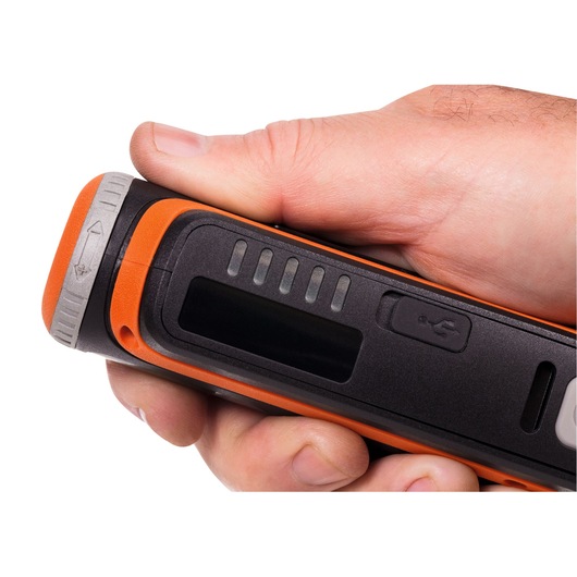 Close-up of a person's hand holding a BLACK+DECKER electronic device in black and orange colors, showing a USB port and indicator lights.