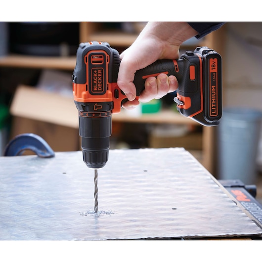 Photo of BLACK+DECKER BDC718AS2F cordless drill with lithium 18V battery drilling metal sheet.