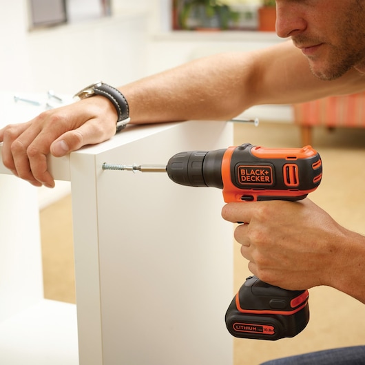 BLACKDECKER BDCD12K cordless drill used to assemble white furniture, close-up photography.