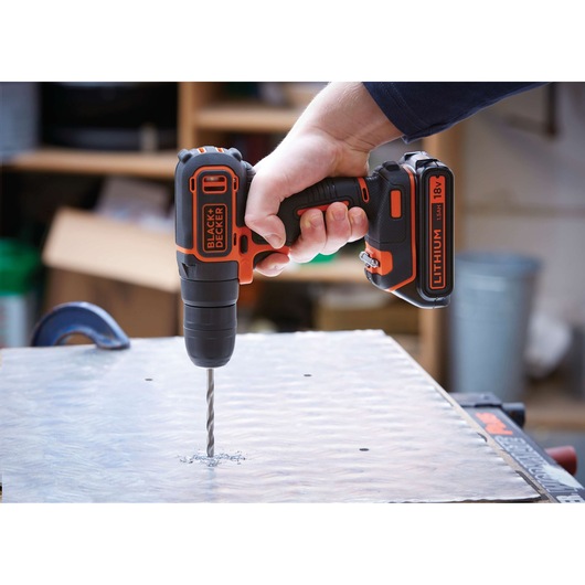 BLACKDECKER BDCD18 cordless drill with 18V lithium battery drilling into metal sheet.