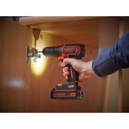 BLACKDECKER BDCD18 cordless drill with LED light in use on cabinet hinge, close-up photography.