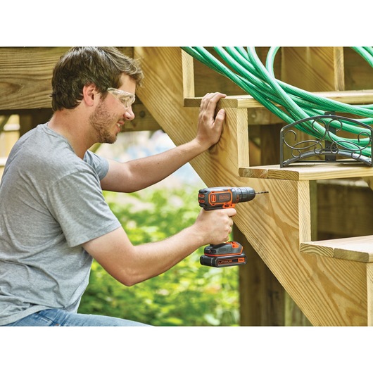 Photo of BLACKDECKER BDCDC18BAFC cordless drill used on wooden stairs outdoors.