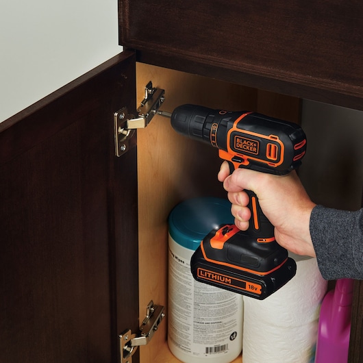 BLACKDECKER BDCDC18BAFC cordless drill being used to fix cabinet hinge.