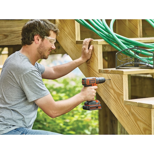 Photo of BLACKDECKER BDCDC18KB cordless drill used on wooden stairs outdoors.