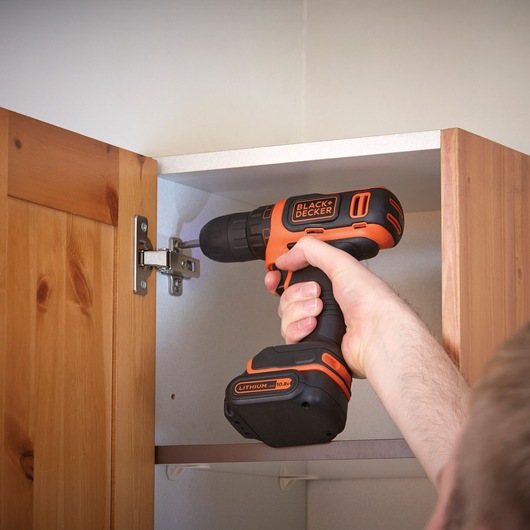 Photo of BLACKDECKER BDCDD12KB cordless drill in use assembling a wooden cabinet.