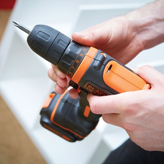 Photo of BLACKDECKER BDCDD12KB cordless drill in hand, black and orange design, close-up view.