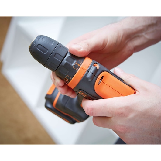 BLACKDECKER BDCDD12 cordless drill in orange and black held in hand, close-up photography.