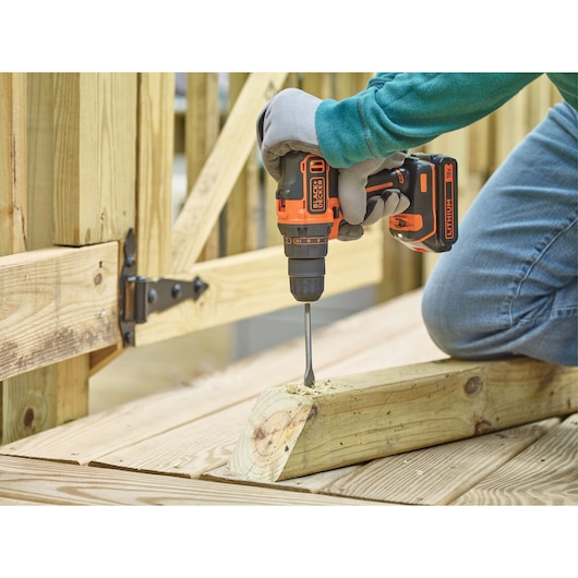 BLACKDECKER BDCDD186B cordless drill in use drilling into wooden beam outdoors.