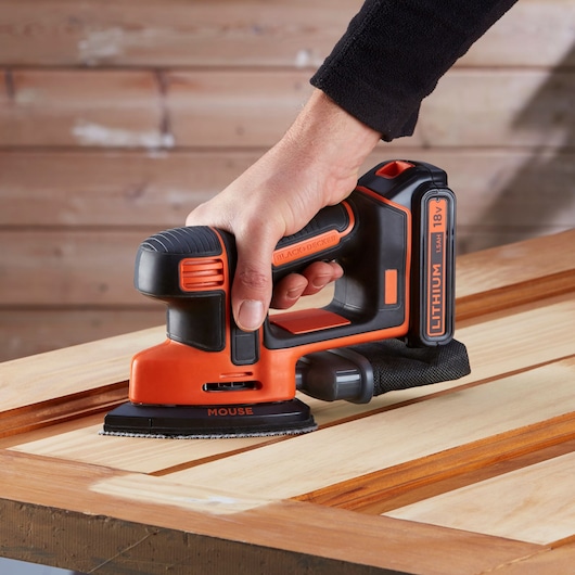 BLACKDECKER BDCDS18 cordless mouse sander in use on wooden surface, close-up side angle.