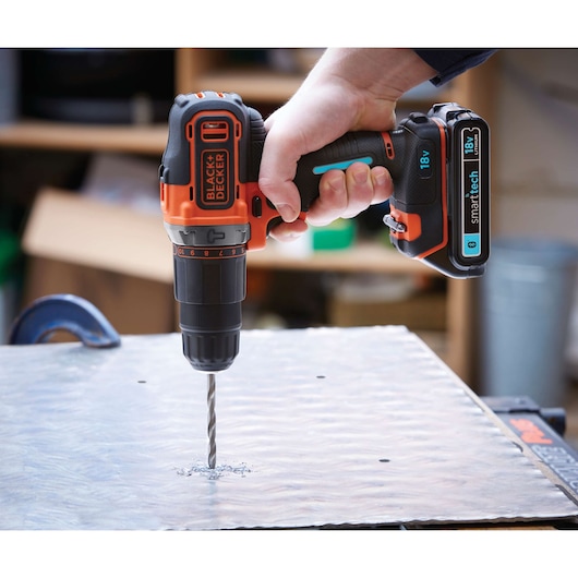 Photo of BLACK+DECKER BDCHD18KST cordless drill in use, drilling into metal sheet