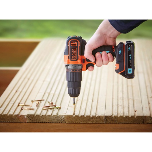 BLACKDECKER BDCHD18KST cordless drill held over wooden planks with screws, side angle.