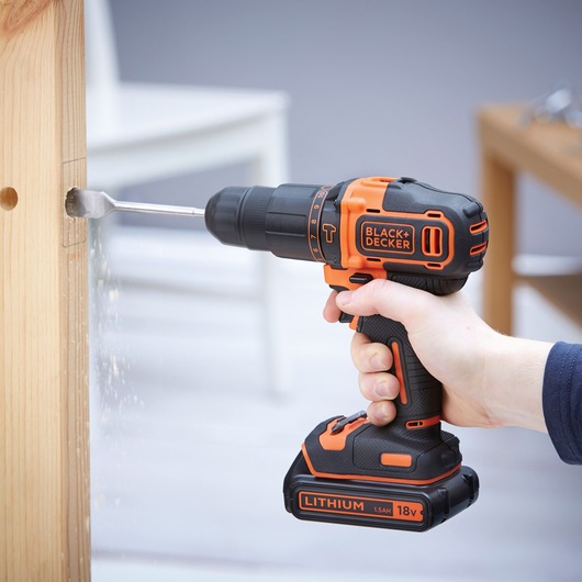Photo of BLACKDECKER BDCHD18K cordless drill being used to drill wood, visible orange and black design.