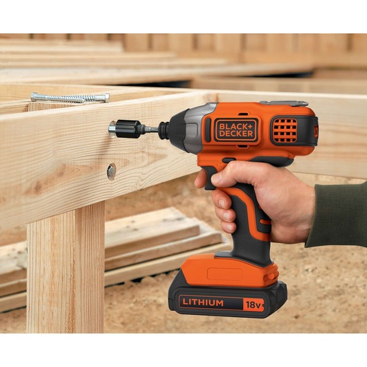 BLACK+DECKER BDCIM18N impact driver 18V used to drive screw into wooden frame, close-up view.