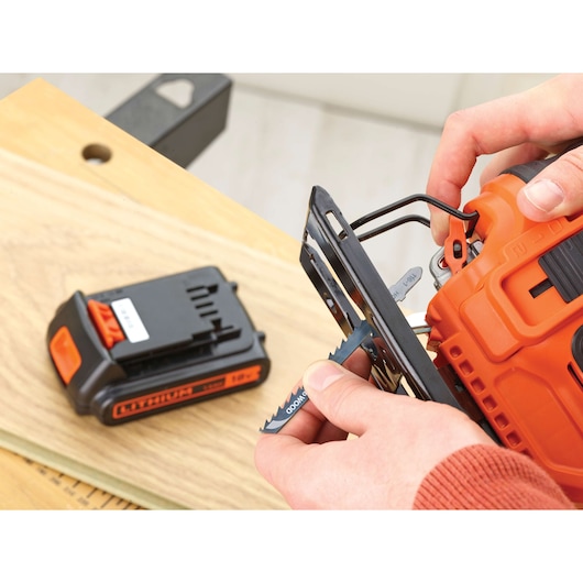 BLACKDECKER BDCJS18N cordless jigsaw close-up with battery and blade being inserted, on wooden surface.