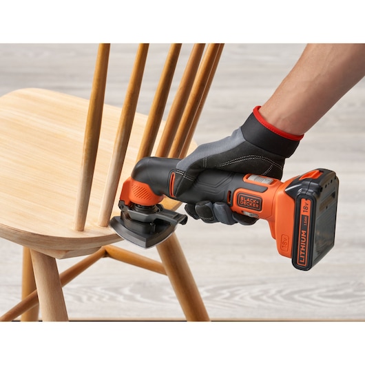 BLACKDECKER BDCOS18D1K cordless oscillating tool sanding wooden chair, close-up side angle.