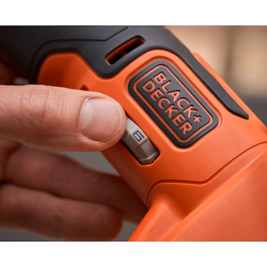 Close-up photo of BLACK+DECKER BDCOS18D1K power tool with finger adjusting speed switch, orange and black design.
