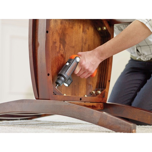 BLACK+DECKER BDCSFL20C cordless screwdriver with orange accents used to assemble wooden furniture indoors.