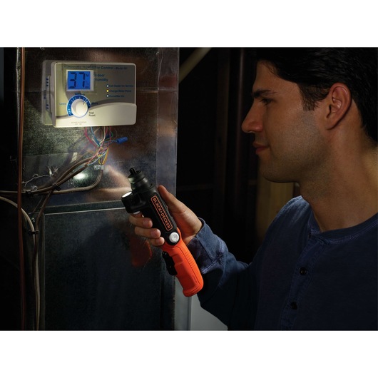Photo of BLACK+DECKER BDCSFL20C cordless screwdriver with LED light used near an electronic control panel.