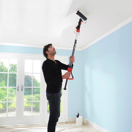 BLACKDECKER BDPR400 paint roller with extension pole used on ceiling in bright room.