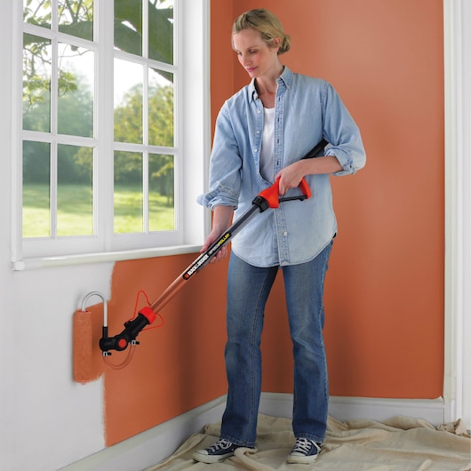 BLACKDECKER BDPR400 paint roller with extension handle used for wall painting indoors.